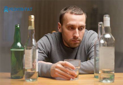 Мужчина сидит и пьет алкоголь
